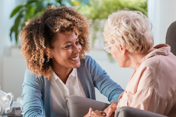 Woman in cardigan speaking with Senior Citizen